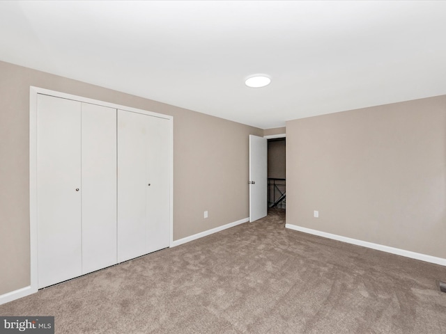 unfurnished bedroom featuring carpet floors, baseboards, and a closet