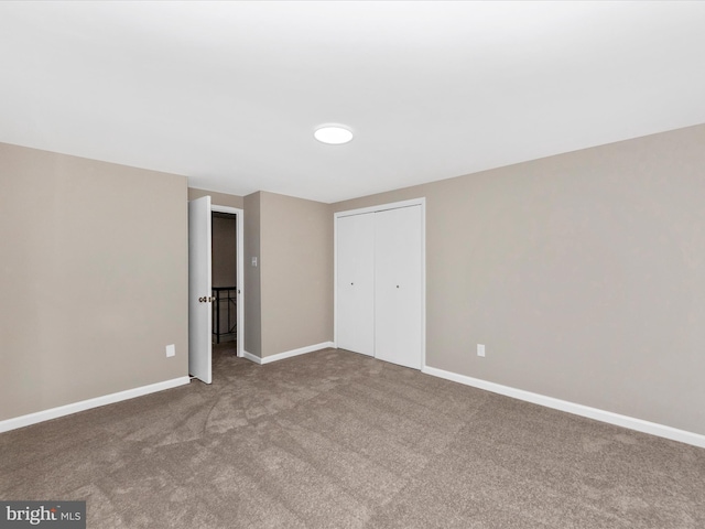 unfurnished bedroom featuring carpet, baseboards, and a closet