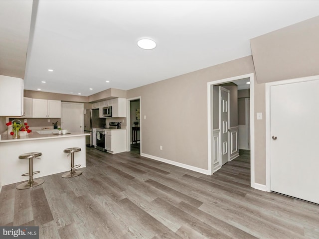 kitchen featuring stainless steel appliances, light wood-style floors, white cabinetry, light countertops, and recessed lighting