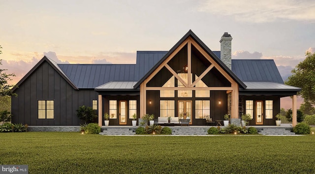 back of property with french doors, board and batten siding, a lawn, a standing seam roof, and metal roof