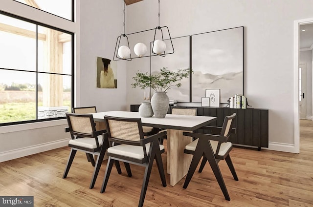 dining space with light wood-style flooring, healthy amount of natural light, baseboards, and a high ceiling