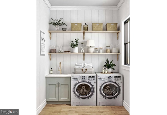 laundry room featuring cabinet space, washing machine and clothes dryer, crown molding, light wood-style flooring, and baseboards