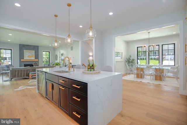 kitchen featuring a sink, recessed lighting, light wood-style flooring, a large fireplace, and dishwasher