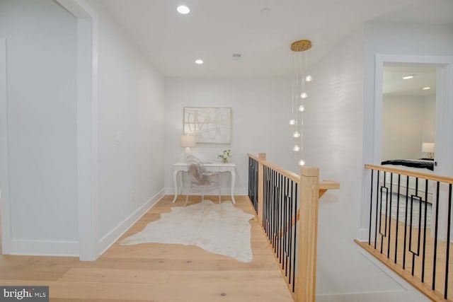 hallway with an upstairs landing, wood finished floors, recessed lighting, and baseboards