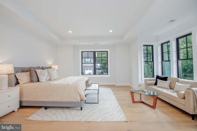 bedroom featuring light wood-style flooring, a raised ceiling, baseboards, and recessed lighting