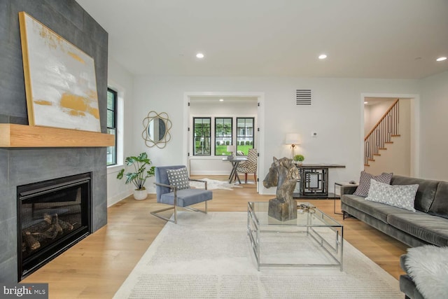 living area featuring stairs, wood finished floors, a fireplace, and recessed lighting