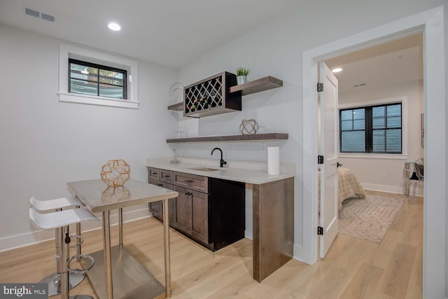 indoor wet bar with light wood finished floors, plenty of natural light, and recessed lighting