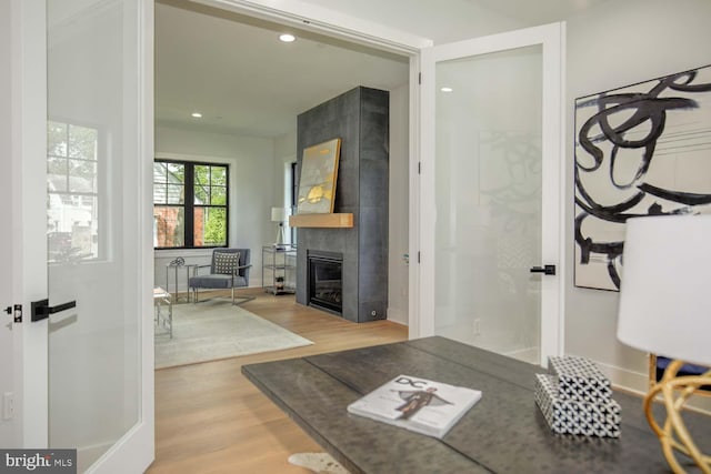 living room with light wood-style flooring, recessed lighting, and a tiled fireplace
