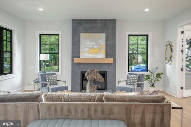 living room featuring wood finished floors, baseboards, a fireplace, and recessed lighting