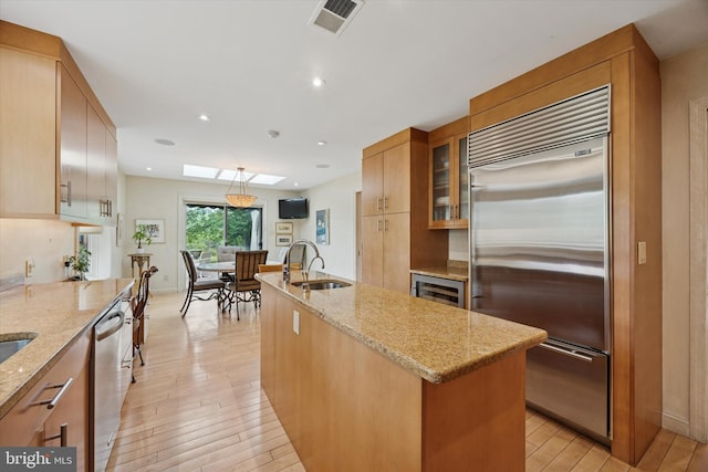 8 Fetlock Ln, Blue Bell, PA 19422 - kitchen featuring stainless steel appliances, a sink, light wood-type flooring, a kitchen island with sink, and beverage cooler