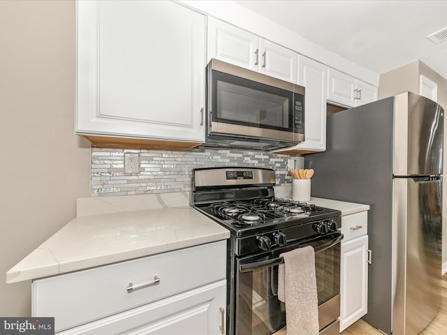 kitchen with stainless steel appliances, tasteful backsplash, white cabinetry, and light stone countertops