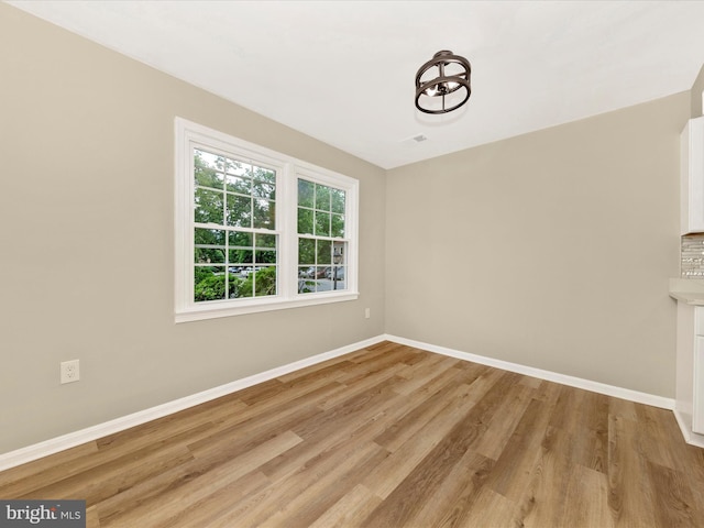 unfurnished dining area with baseboards and light wood-style floors