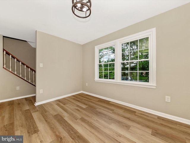 unfurnished room featuring wood finished floors, baseboards, and stairway