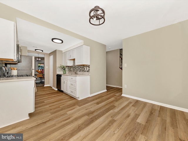 kitchen with a sink, decorative backsplash, baseboards, and light countertops