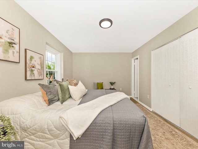 bedroom with wood finished floors, a closet, and baseboards
