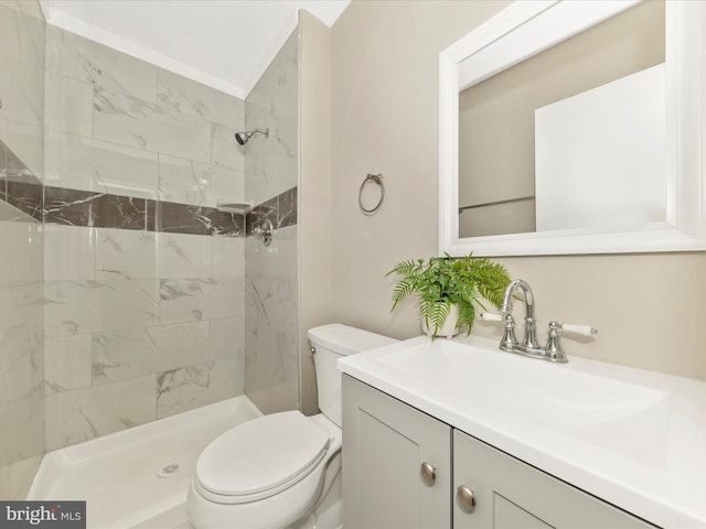 bathroom featuring toilet, tiled shower, and vanity