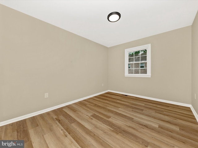 spare room with baseboards and light wood-style floors