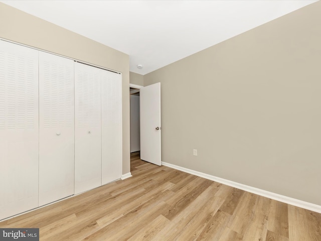unfurnished bedroom with light wood finished floors, baseboards, and a closet