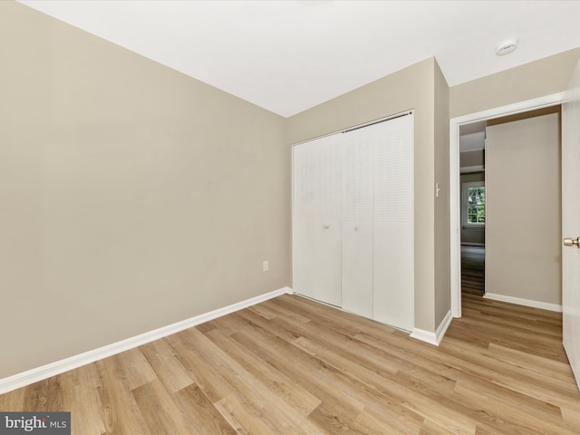 unfurnished bedroom with light wood-type flooring, baseboards, and a closet