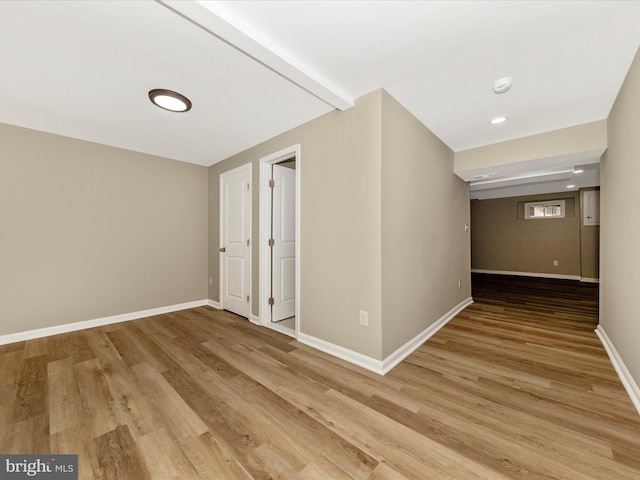 unfurnished room featuring baseboards, light wood finished floors, and a smoke detector