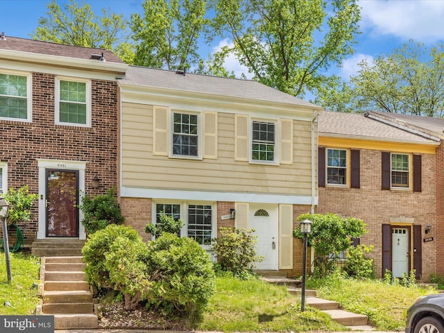 view of front of home featuring brick siding and roof with shingles