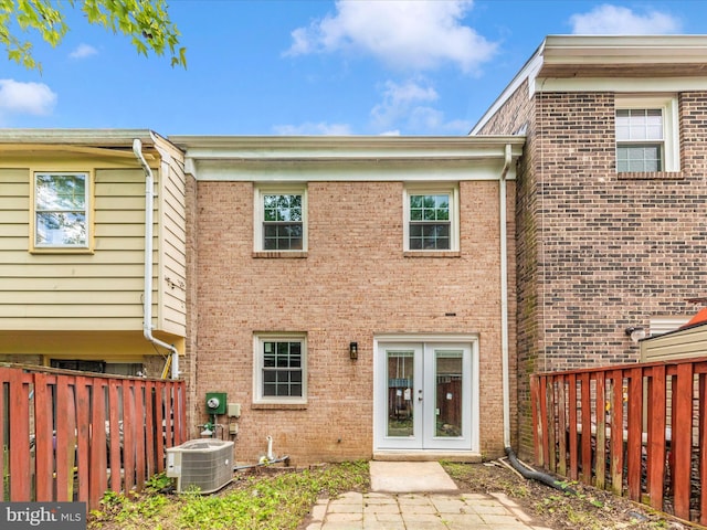 back of property with cooling unit, french doors, fence, and brick siding