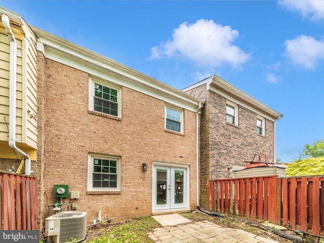 back of property with french doors, central AC unit, brick siding, and fence
