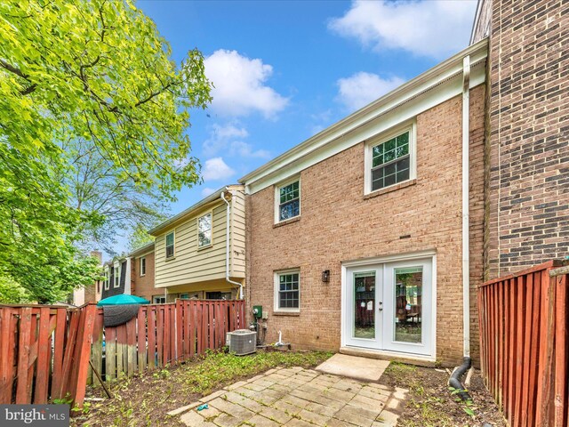 rear view of house featuring french doors, a fenced backyard, brick siding, central AC unit, and a patio area