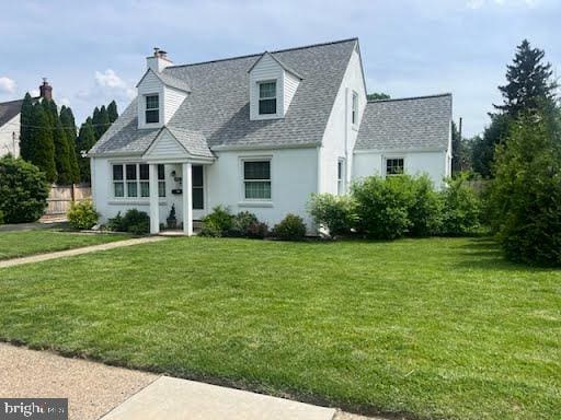 1381 Burmont Rd, Drexel Hill, PA 19026 - cape cod-style house with a front lawn, stucco siding, a shingled roof, and a chimney