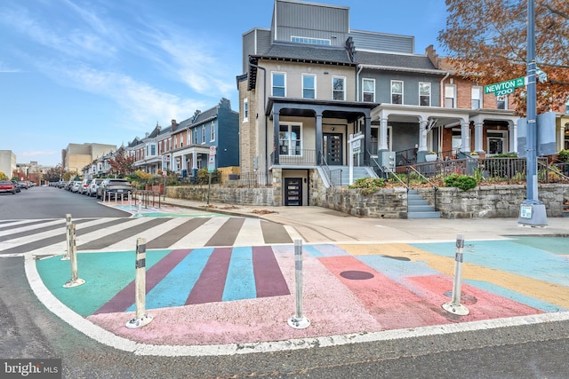 view of asphalt street with sidewalks, a residential view, stairway, and street lights