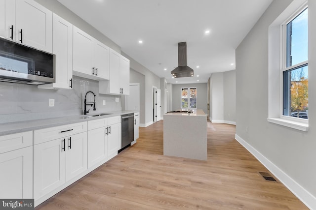 kitchen featuring a sink, stainless steel appliances, island range hood, light countertops, and white cabinets