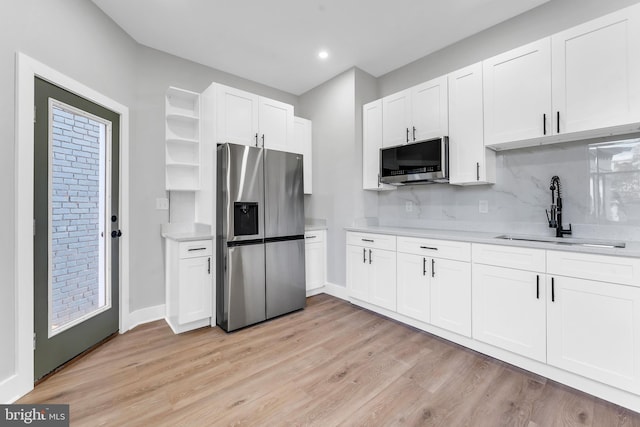 kitchen with appliances with stainless steel finishes, a sink, light countertops, light wood-style flooring, and recessed lighting
