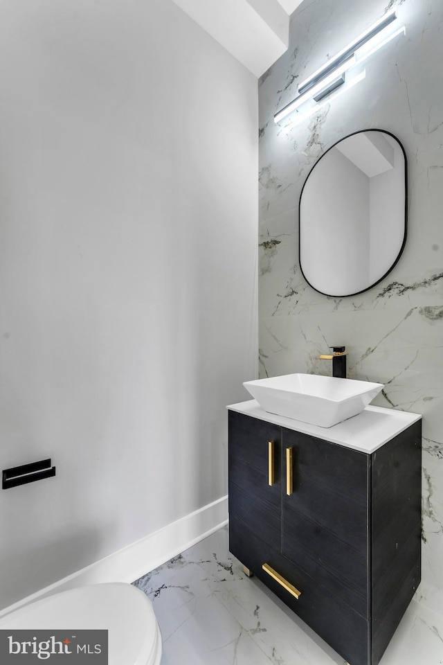 bathroom featuring marble look tiles, vanity, toilet, and baseboards