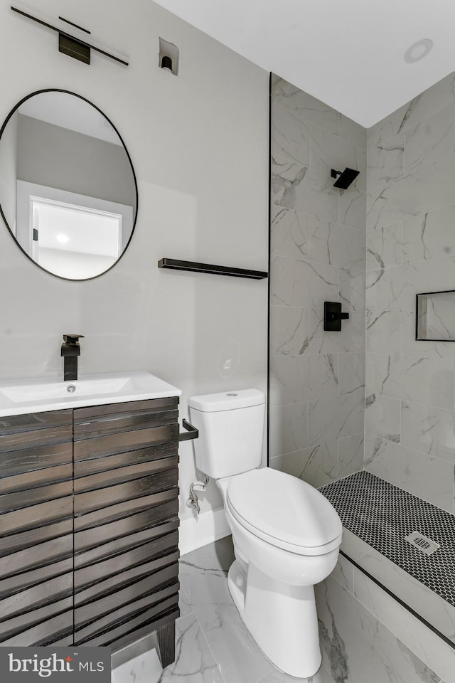 bathroom with marble look tiles, toilet, a tile shower, and vanity