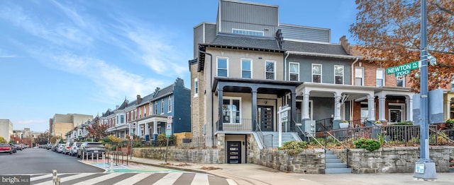multi unit property with a porch, a residential view, and roof with shingles