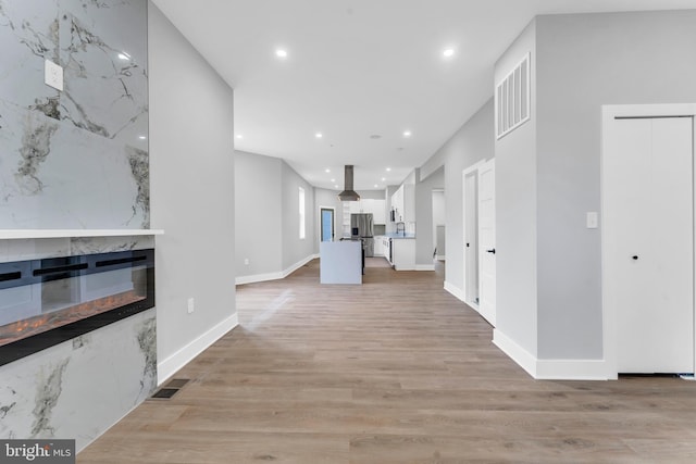 unfurnished living room with recessed lighting, light wood-style floors, baseboards, and a fireplace