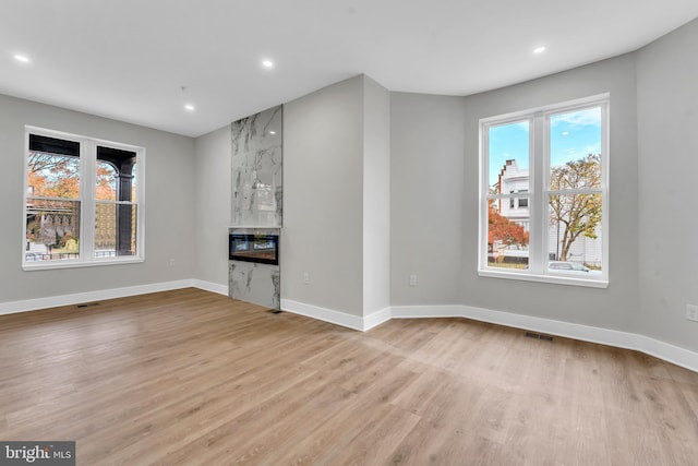 unfurnished living room with wood finished floors, a fireplace, baseboards, and recessed lighting