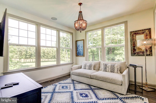 living room featuring baseboards, a chandelier, and dark wood-type flooring