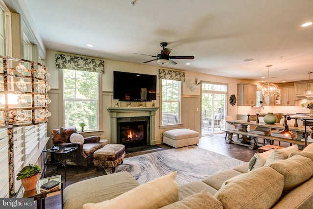 living area with wood finished floors, a fireplace with flush hearth, a decorative wall, ceiling fan, and wainscoting