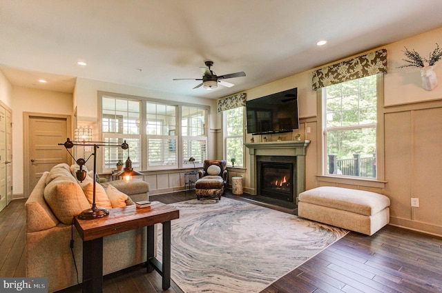 living room featuring dark wood finished floors, a fireplace with flush hearth, a ceiling fan, a decorative wall, and recessed lighting