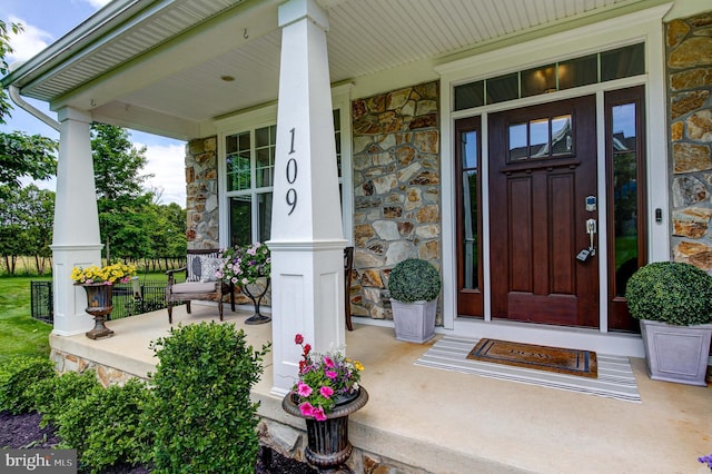 doorway to property with stone siding and covered porch