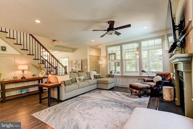 living room featuring stairway, a ceiling fan, wood finished floors, a fireplace, and healthy amount of natural light