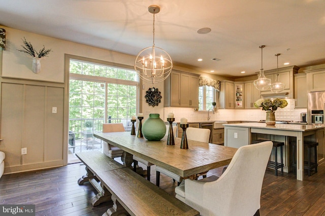 dining space featuring dark wood-style flooring, a chandelier, a decorative wall, recessed lighting, and wainscoting