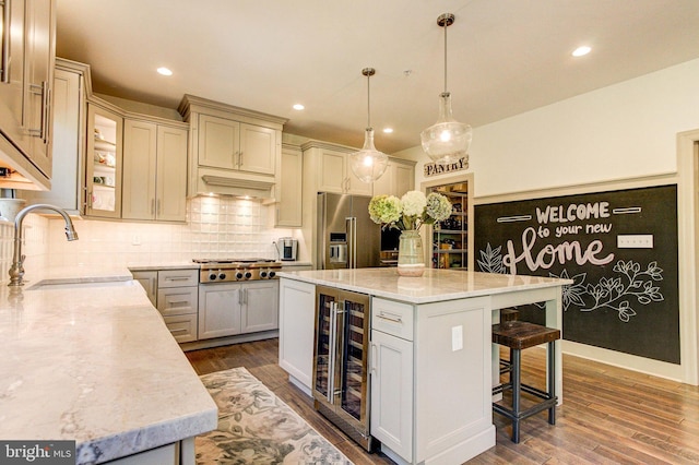 kitchen featuring wine cooler, appliances with stainless steel finishes, a sink, dark wood finished floors, and a kitchen bar