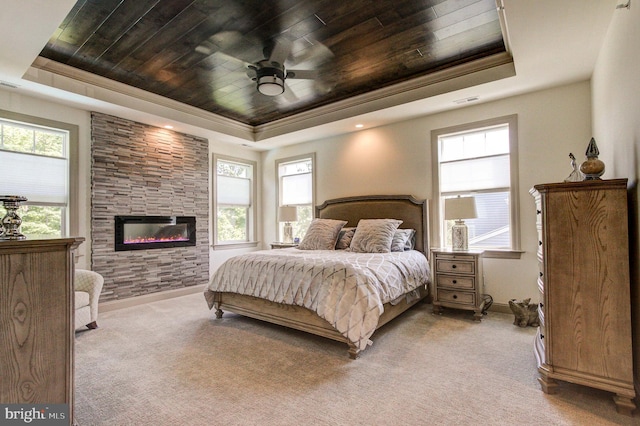 carpeted bedroom with a tray ceiling, wood ceiling, a large fireplace, baseboards, and crown molding