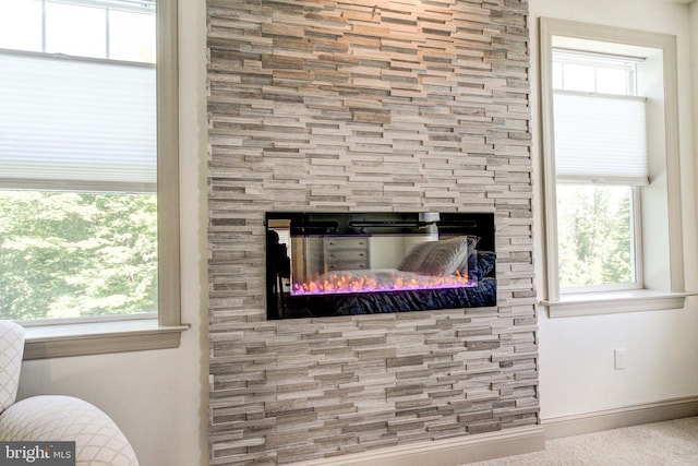 detailed view of a fireplace, baseboards, and carpet