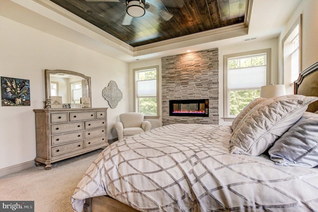 bedroom with a raised ceiling, wood ceiling, baseboards, light colored carpet, and a fireplace