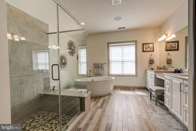 bathroom featuring vanity, a stall shower, healthy amount of natural light, and a soaking tub