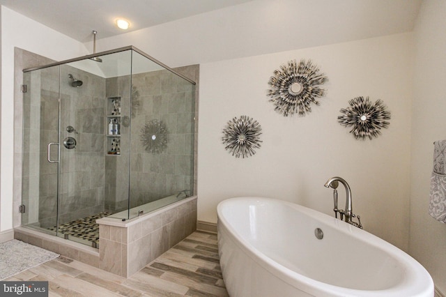 full bathroom featuring a shower stall, a freestanding tub, and wood finished floors