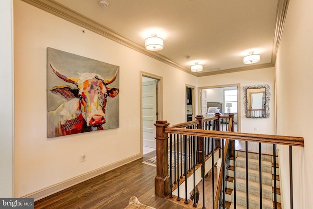 hall with an upstairs landing, crown molding, hardwood / wood-style flooring, and baseboards
